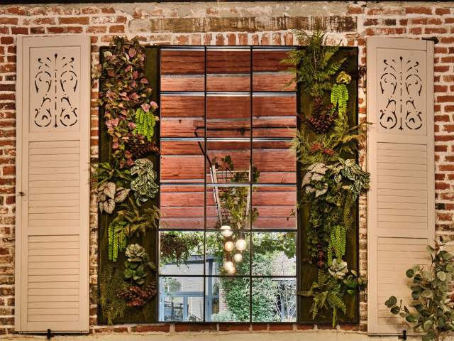 Mur végétal luxuriant encadrant une grande fenêtre intérieure aux reflets dorés – Restaurant avec terrasse Douai