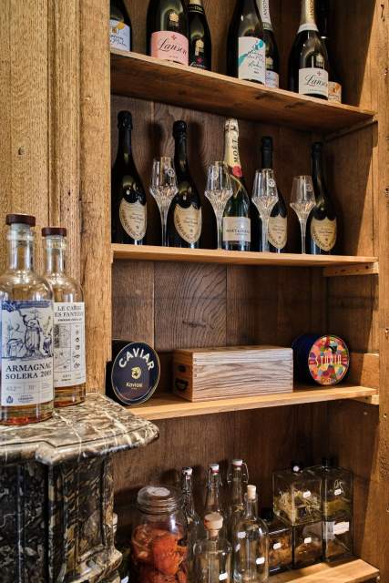 Étagère en bois avec bouteilles de gin, champagnes et verres à pied alignés – Restaurant Gastronomique Douai