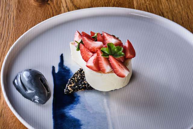 Dessert fraise et crème sur socle de graines noires dans assiette bicolore bleue – Restaurant Bistronomique Douai