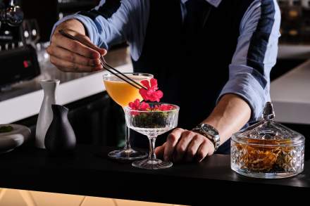 Bartender déposant une fleur rouge sur un cocktail en coupe, service bar – Boterzing Douai