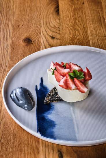 Dessert à la fraise sur lit de crème, décor chocolat et menthe fraîche dans une assiette bleue – Boterzing Douai