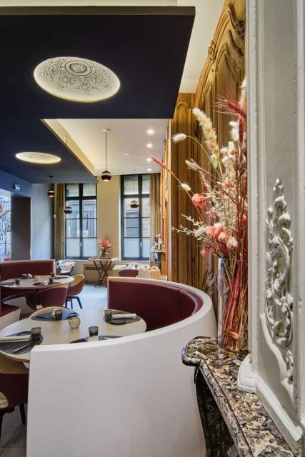 Grande salle en rotonde avec banquettes bordeaux, colonnes dorées et décoration florale – La Table des Échevins Douai