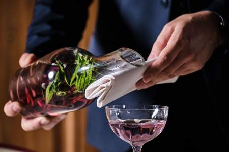 Serveur versant un cocktail violet depuis une carafe sur coupe givrée, service en salle – Maison Prevost Douai
