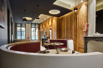 Salle de restaurant avec banquettes bordeaux, boiseries chaleureuses et tables dressées – La Table des Échevins Douai