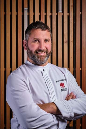 Chef en veste blanche souriant, portrait officiel devant boiserie – Jérôme Prévost Douai