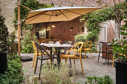 Terrasse ensoleillée avec tables dressées, parasol et jardin fleuri en centre-ville – Restaurant avec terrasse Douai