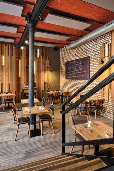 Salle de restaurant avec murs en briques, tables bois, ardoise murale et escalier métal – Boterzing Douai