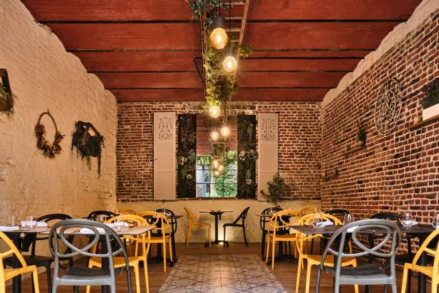 Salle en briques avec poutres bois, chaises bistrot dorées et suspensions ampoules – Boterzing Restaurant Bistronomique Douai