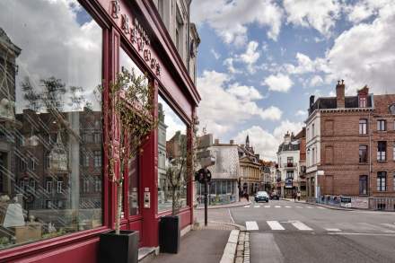 Façade rouge de Maison Prevost en angle de rue, centre-ville de Douai avec ciel nuageux – Restaurant Douai Centre-ville
