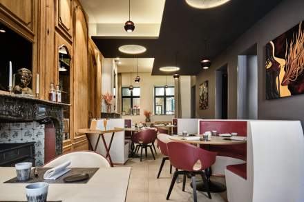 Vue d'ensemble de la salle, tables rondes et chaises bordeaux sous plafond design – Restaurant Douai Centre-ville